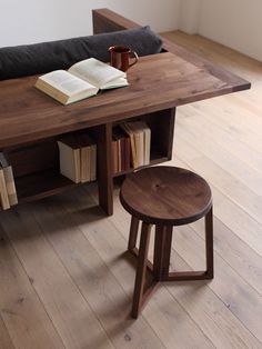 a wooden table with two stools and an open book sitting on top of it