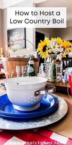 a blue plate topped with a colander next to a vase filled with yellow flowers