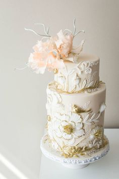 a wedding cake with white and gold flowers on the top is featured in an instagram