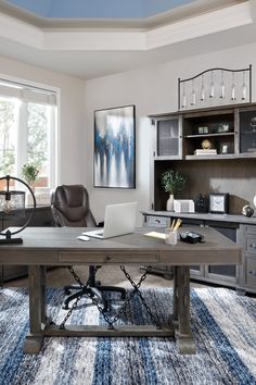 a desk with a laptop on top of it in front of a book shelf and window