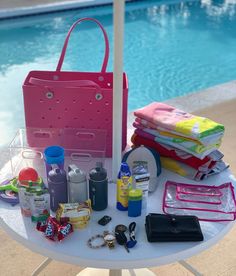 a pink bag sitting on top of a table next to a swimming pool filled with items