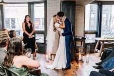 a bride and groom kiss as they stand in front of an audience at their wedding ceremony