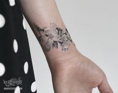 a woman's arm with a flower tattoo on the left side of her wrist