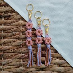 two pink and blue tasselled flowers are hanging from gold - plated hooks