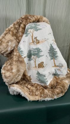 a teddy bear wrapped in a blanket sitting on top of a green table next to a curtain