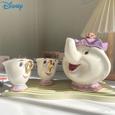 the beauty and the beast teapots are on display in front of a lamp