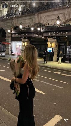 a woman is walking down the street holding flowers