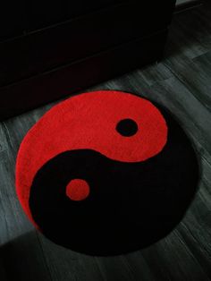 a black and red area rug with a yin symbol on the floor next to a couch