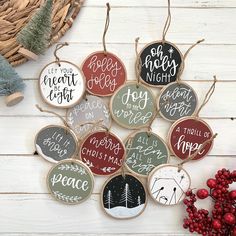 a bunch of christmas ornaments hanging on a white wooden wall next to some red berries