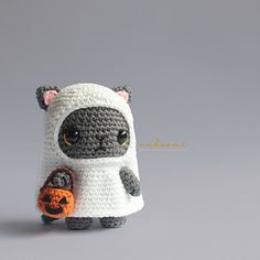 a small crocheted cat with a pumpkin in it's hand is shown