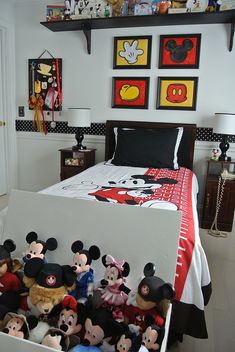 a bed with mickey mouse pictures on the wall and other stuffed animals in a box