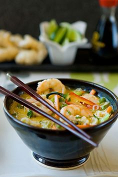 a bowl of shrimp and vegetable soup with chopsticks in front of the bowl