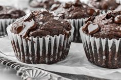 several chocolate muffins are sitting on a silver platter with white frosting