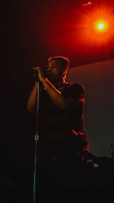 a man standing in front of a microphone on top of a red and black stage