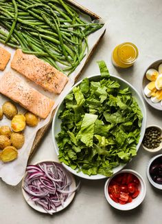 fish, vegetables and other foods are laid out on the table to be prepared for dinner