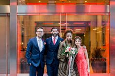 a group of people standing in front of a glass building with red lights behind them