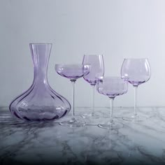 four wine glasses and a vase on a marble table