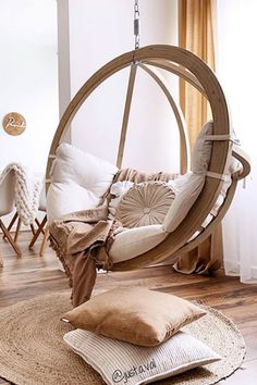 a chair that is hanging in the air with pillows on it and some chairs around