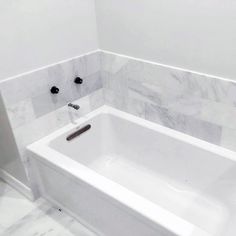 a white bath tub sitting inside of a bathroom next to a wall mounted faucet