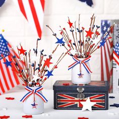 two vases filled with sticks and red white and blue decorations on top of a table