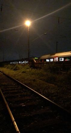 an empty train track at night with the lights on