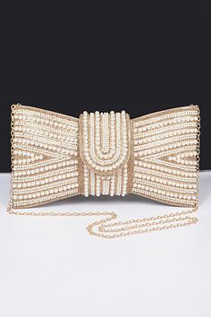 Intricate pearl and bead detailing Bow-shaped design for a bold look Magnetic flap closure Ideal for Dressed up Night Out 10.75"W x 6"H x 1"D Polyurethane/ Rhinestone, Mixed Metal Introducing this luxurious beaded clutch that doubles as a statement accessory. Adorned with intricate pearl and bead detailing, this clutch is shaped like an elegant bow, perfect for adding glamour to evening or formal wear. Its structured design ensures it stands out, while the magnetic flap closure keeps your essent Glamorous Clutch With Pearl Embroidery, Gold Pearl Clutch For Parties, Party Embellished Pearl Evening Bag, Gold Pearl Party Clutch, Party Gold Pearl Clutch, Pearl Clutch For Party, Party Clutch With Pearl Embroidery In Gold, Pearl Beaded Evening Bag For Formal Occasions, Party Gold Clutch With Pearl Embroidery