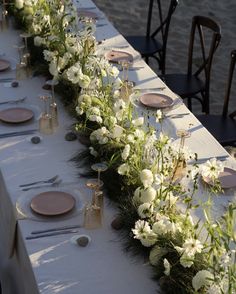 a long table with flowers and place settings on it