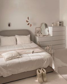 a bed with white sheets and pillows in a bedroom next to a dresser filled with shoes