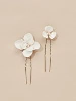 three white flowers are placed on top of each other in the shape of hair pins