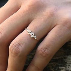 a woman's hand with a ring on it and two small flowers in the middle