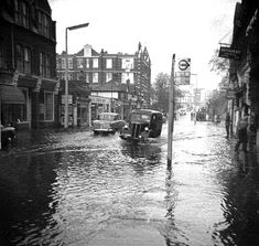 cars driving down a flooded street in front of buildings