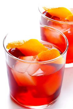 two glasses filled with red liquid and orange slices