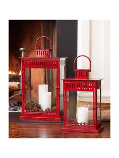 two red lanterns sitting next to each other on a wooden floor in front of a fireplace