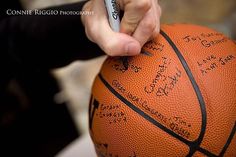 a person holding a basketball with writing on it and pointing to the ball in front of them