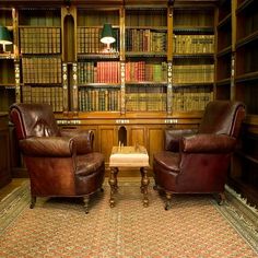 two leather chairs sitting in front of a bookshelf