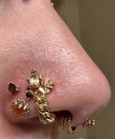 a close up of a person's nose with gold jewelry on it and piercings