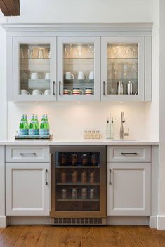 a kitchen with white cabinets and wood flooring is pictured in this image, there are bottles on the counter