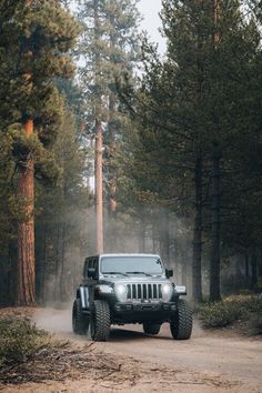 a jeep driving down a dirt road in the woods