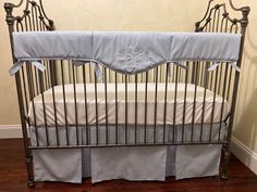 a metal crib with a blue and white bedding on top of it in a room