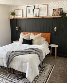 a bed with white sheets and pillows on top of it next to a black wall