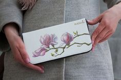 a woman holding a wallet with flowers painted on it