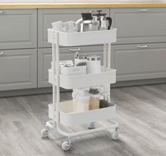 a kitchen cart with two trays on it in the middle of a floored room