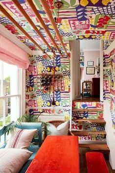 colorfully decorated living room with red couches and patterned wall paper on the ceiling