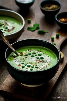 two bowls filled with green soup on top of a wooden table