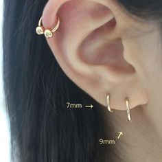 a woman's ear is shown with two small gold hoops