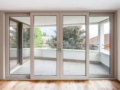 an empty room with sliding glass doors and wood flooring, overlooking a balcony area