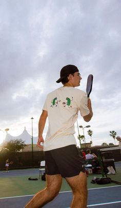 a man holding a tennis racquet on top of a tennis court with people in the background