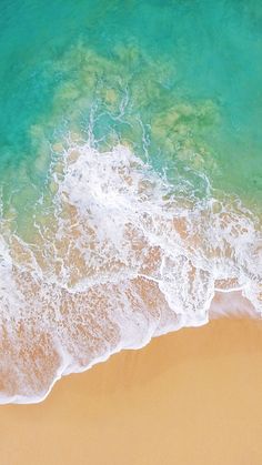 an aerial view of the ocean and beach with waves crashing on it's shore