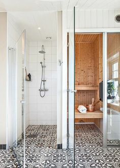 a bathroom with black and white flooring and wooden paneled walls, along with a walk in shower