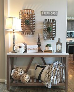 a table with pillows and other items on it in front of a white wall that says farmhouse